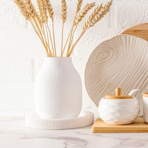 front view of beautiful kitchen utensils and white vase with ears of corn on the kitchen countertop