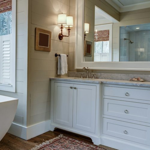 Luxury bathroom with large white tub, beautiful cabinets, and shiplap walls.