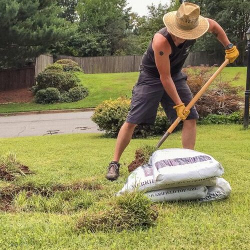 A fit GenX homeowner tends to some DIY landscaping in the front yard on a hot summer day.